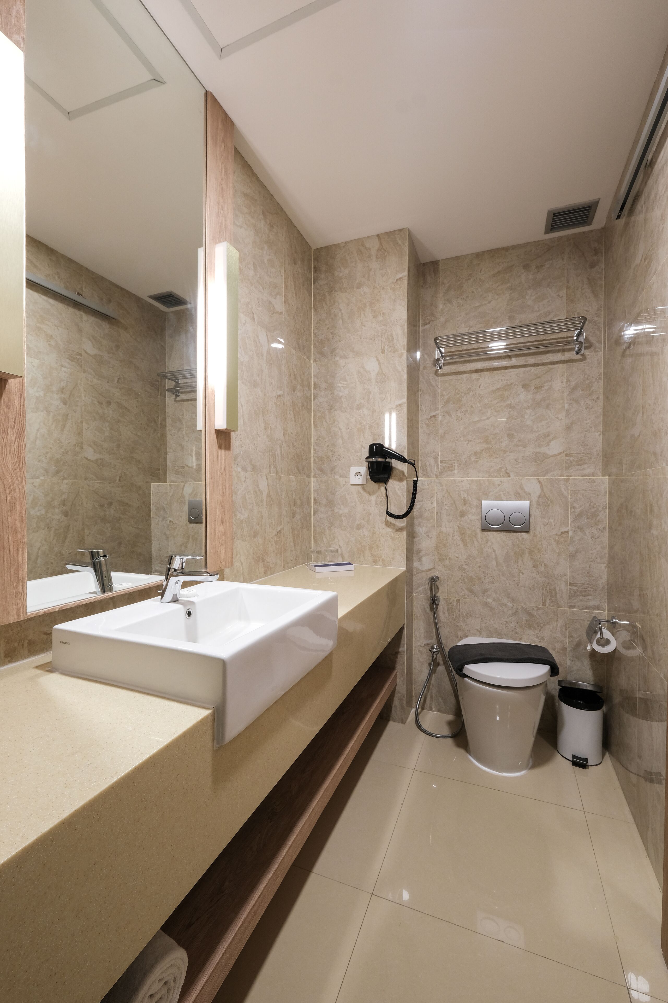 Un baño moderno con un espejo grande, un lavabo, una ducha y un inodoro.