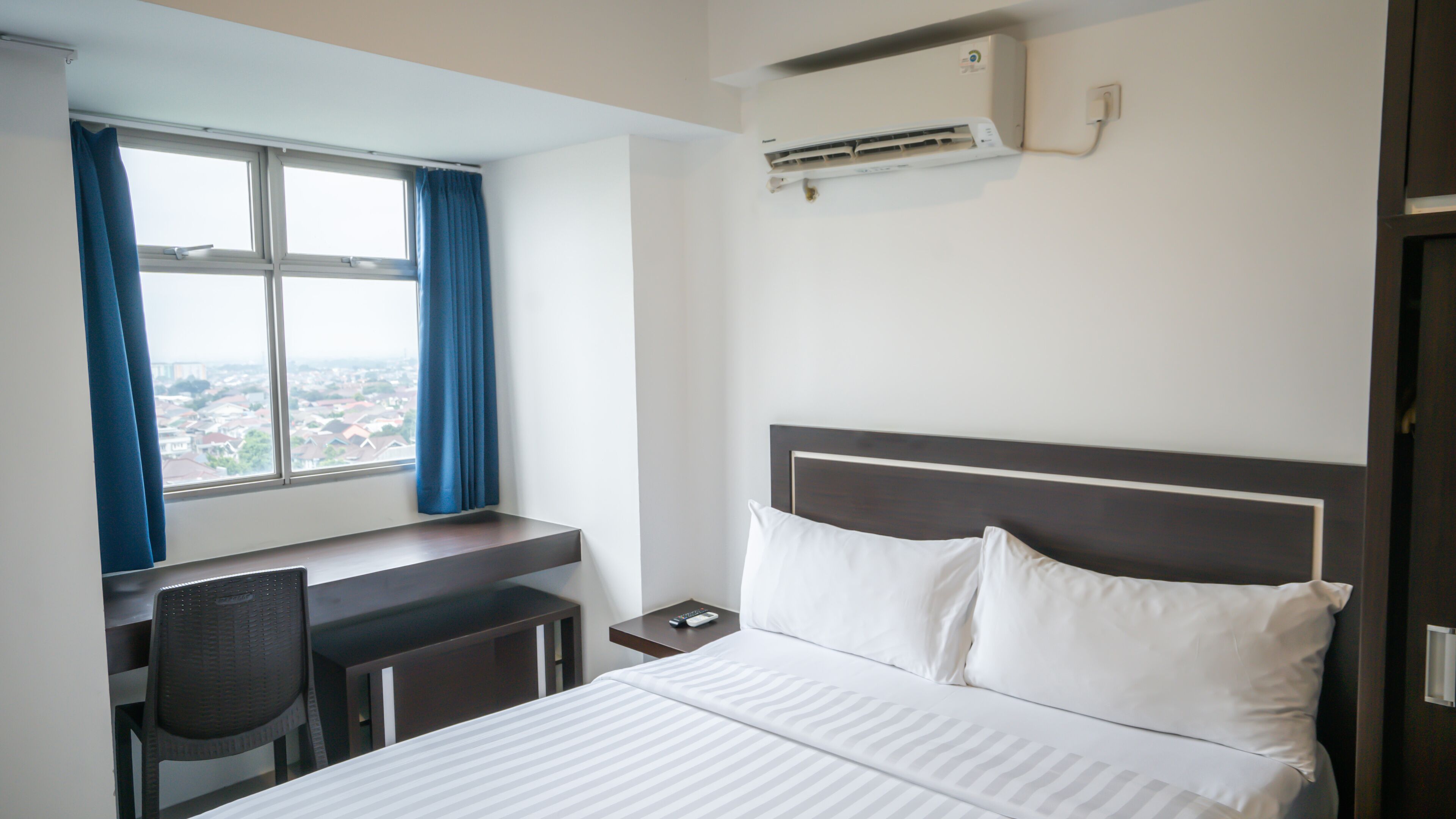 Une chambre d’hôtel avec un lit, un bureau et une fenêtre avec des rideaux.