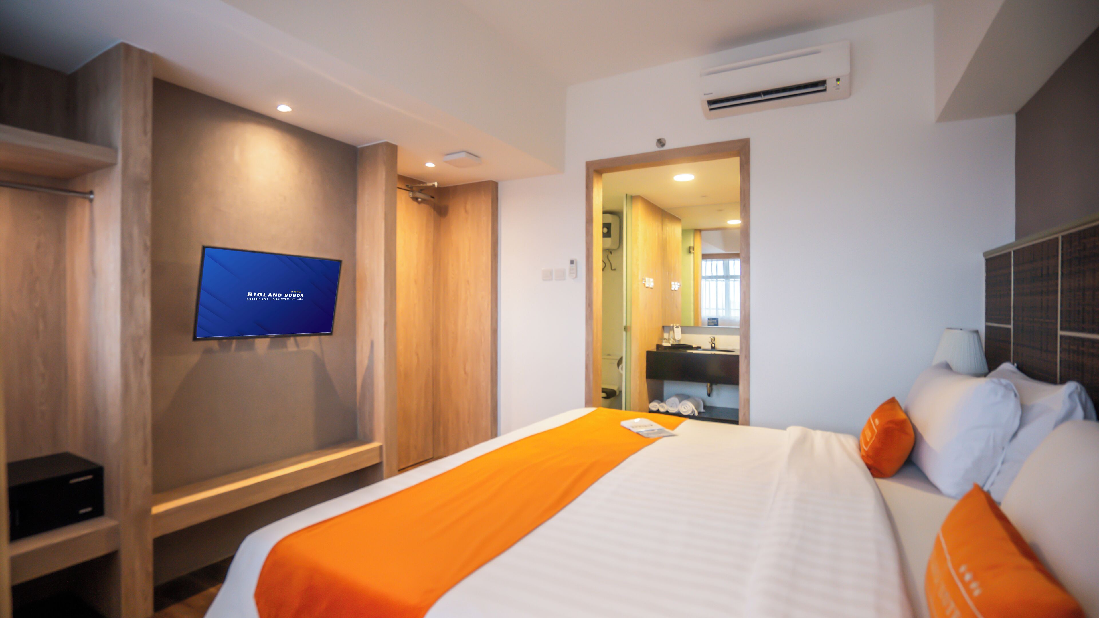 A hotel room with a bed, a television, a wardrobe, and a bathroom visible through an open door.