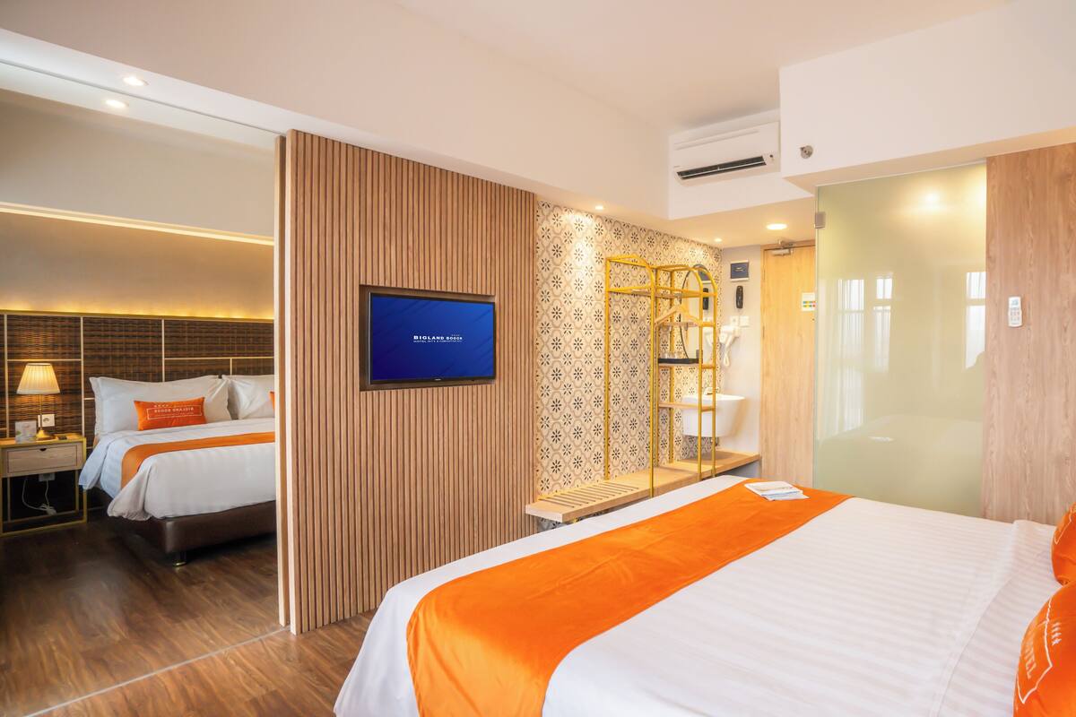 A hotel room with a bed, a TV, a mirror, and a wooden panel wall.