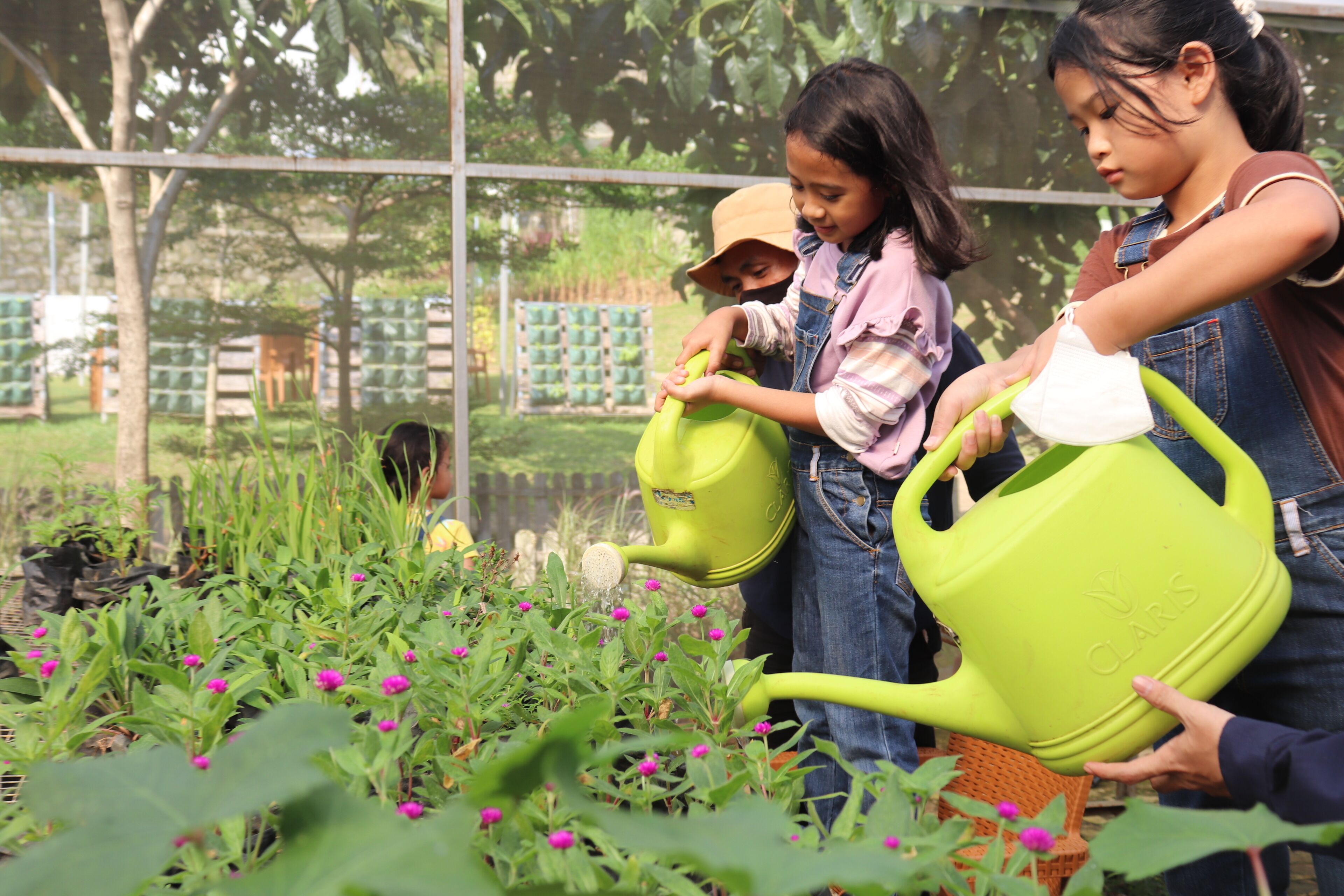 Un jardín con niños regando plantas.