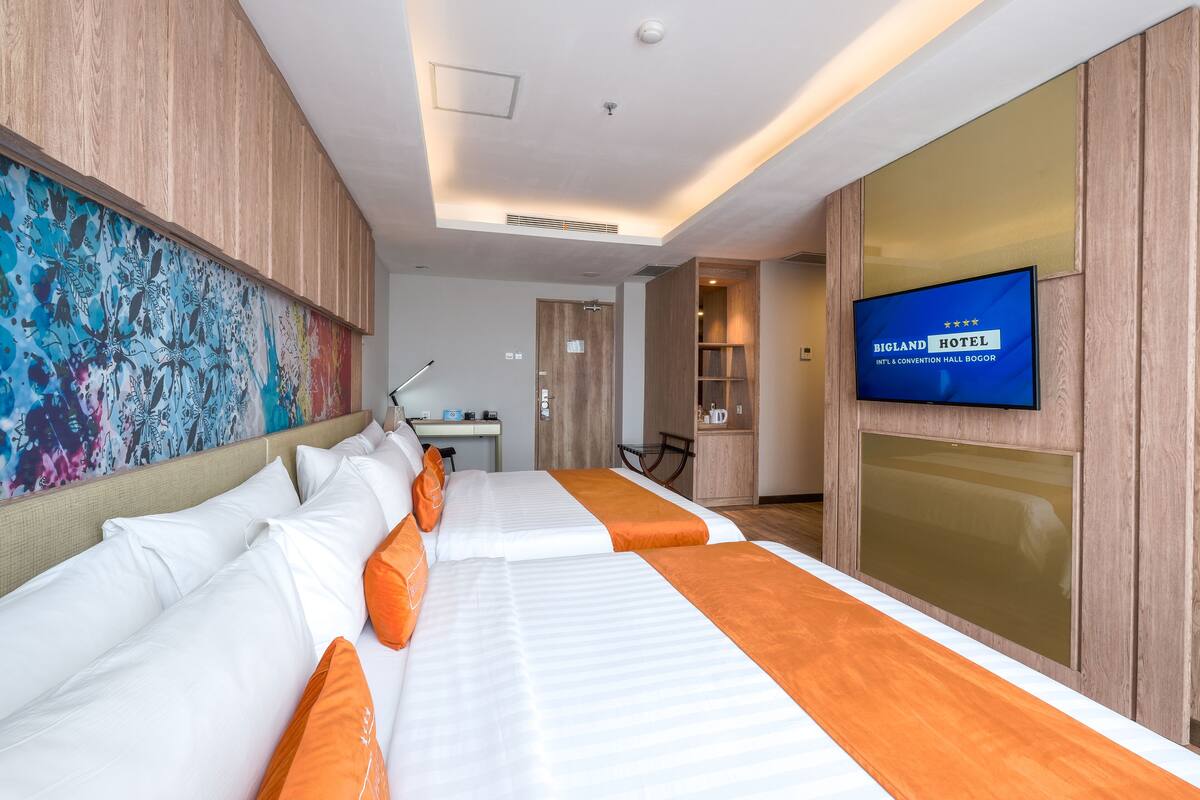 A hotel room with two beds, a TV, and a desk.
