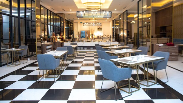 A modern restaurant with a checkered floor, multiple tables, and chairs. - Bigland Bogor Hotel Powered by Archipelago (Bogor)