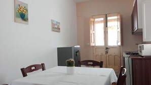 Ein kleiner Essbereich mit Tisch für zwei Personen, einem Kühlschrank, einer Mikrowelle und einer Tür mit Fenster.