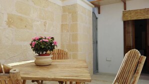 Ein Holztisch mit einem Blumentopf, einem Stuhl und einer Steinwand im Hintergrund.