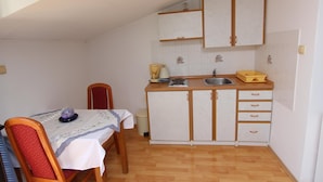 Una cucina compatta con tavolo, sedie e un piccolo piano di lavoro con lavandino.