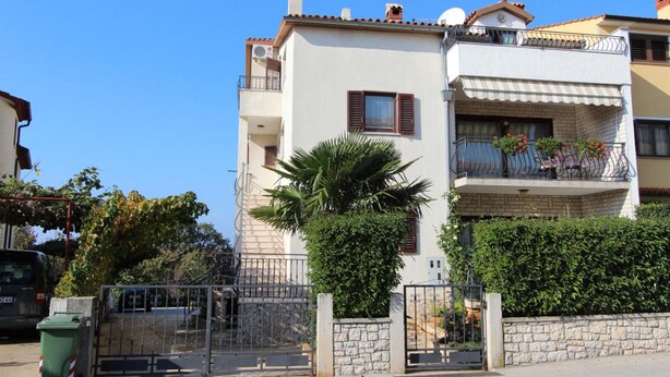 Un edificio residenziale a più piani con balconi, un muro in pietra e un cancello in metallo.