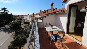 Un balcone con tavolo e sedie, una pianta in vaso e vista sulle case vicine.