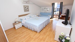 Camera da letto con due letti, una scrivania, una televisione e un piccolo balcone.