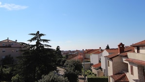 Quartiere residenziale con diverse case, alcune con tetti in tegole rosse, e un grande albero in primo piano.