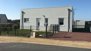 A modern two-story building with a flat roof, a small porch, and a fenced yard.