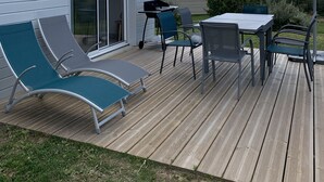 A deck with outdoor furniture, including lounge chairs and a table with an umbrella.