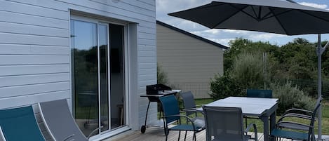 A deck with outdoor furniture, including lounge chairs and a table with an umbrella.