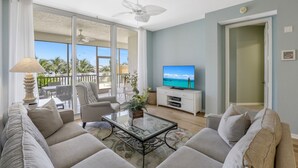 Uma sala de estar espaçosa, com uma televisão grande, assentos confortáveis e uma varanda com vista.