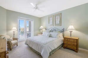 A bedroom with a bed, two bedside tables with lamps, a chair, a wooden dresser, and a ceiling fan. - Regatta - Walking Distance to the Beach! (Naples)