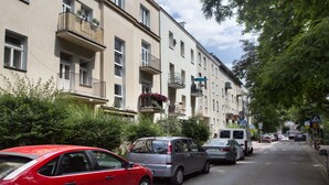 A street lined with multi-story buildings, parked cars, and pedestrian crossings. - P&O Apartments Siewierska (Warsaw)