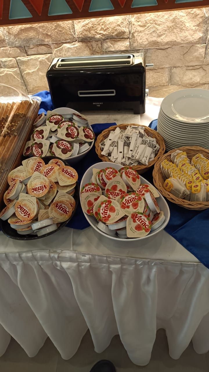 Ein reichhaltiges Buffet mit verschiedenen Speisen, darunter Joghurtbecher, Brot und Brötchen.