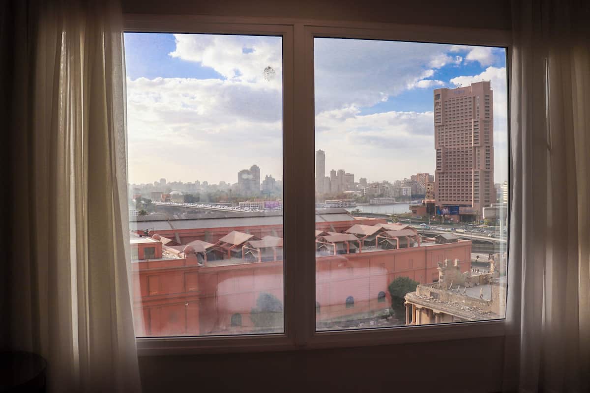 A view from a window with a cityscape in the background, including a tall building and a bridge.