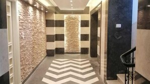 Un pasillo con piso de diseño en zigzag, pared de piedra a la izquierda y una puerta oscura a la derecha.
