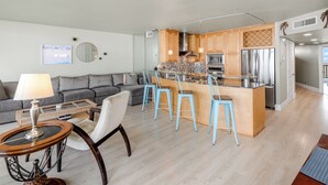 Una cocina moderna con armarios de madera, electrodomésticos de acero inoxidable y una isla central con taburetes de bar.