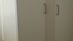 A closed wardrobe with a single handle and a small shelf at the top.