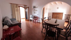 Ein Wohnzimmer mit einer Couch, einem roten Tisch und einem Essbereich mit Tisch und Stühlen.