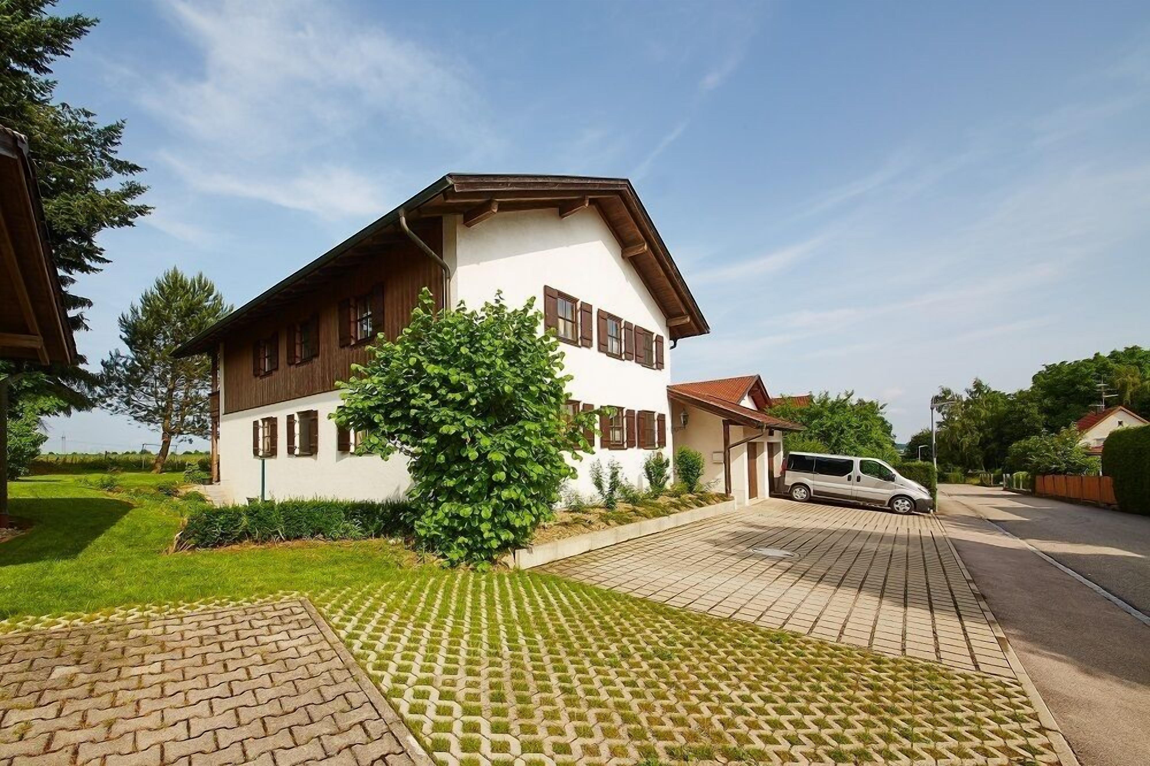 A two-story house with a white exterior and brown trim, a driveway, and a parked van.
