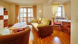 A cozy living room with a sofa, a wooden table, and a window with curtains.