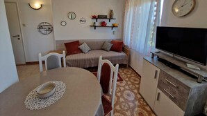 Uma sala de estar acolhedora com sofá, televisão e um espaço de jantar com mesa e cadeiras.
