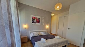Quarto com cama, mesas de cabeceira, guarda-roupa e obras de arte nas paredes.