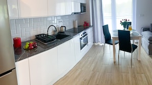 Una cocina moderna con armarios blancos, encimera negra y un comedor con mesa y sillas.
