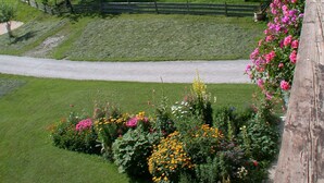 A view of a mountainous landscape with a wooden building and a garden with flowers. - Ferienwohnung Heuberg mit 1 Separaten Schlafzimmer (Samerberg)