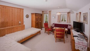 A room with a bed, a desk with a computer, a TV, and a chair. - Ferienwohnung Heuberg mit 1 Separaten Schlafzimmer (Samerberg)