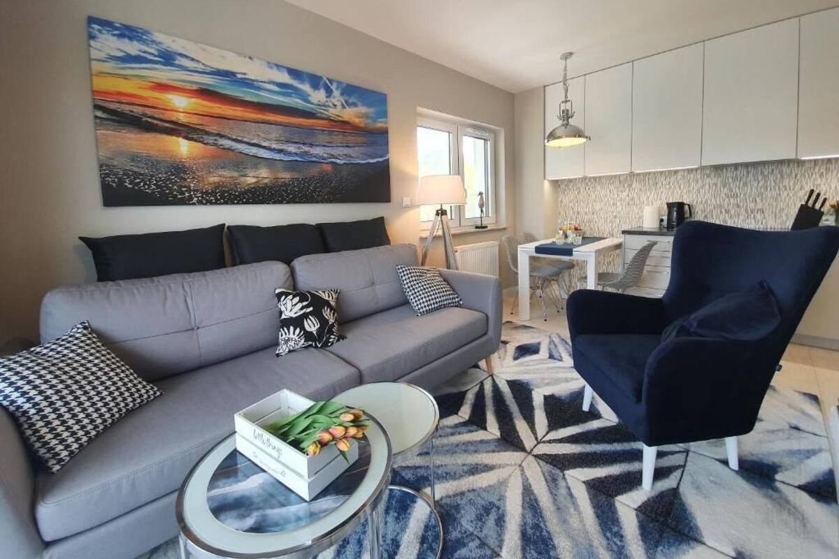 Un salon moderne avec un canapé gris, un fauteuil bleu et une table basse sur laquelle est posé un vase de tulipes.