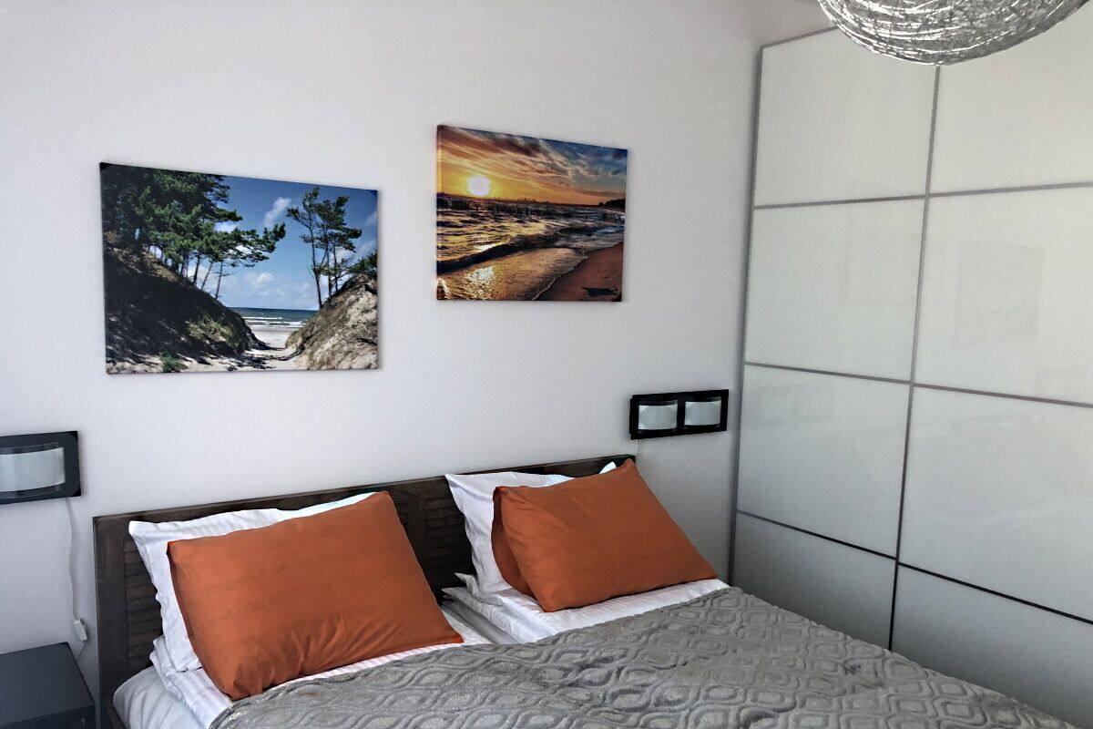 Une chambre à coucher avec un lit, deux oreillers, une tête de lit et deux tableaux accrochés au mur.
