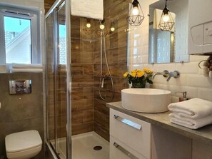 Standaard appartement | Badkamer | Een douche, een haardroger, handdoeken, toiletpapier