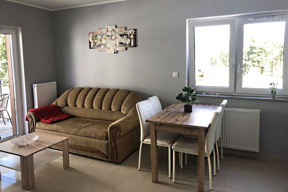 Un salon avec un canapé marron, une table à manger en bois et un plaid rouge.