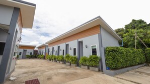 A row of modern hotel buildings with a covered walkway and potted plants. - OYO 1121 Phuree Resort (Sattahip)