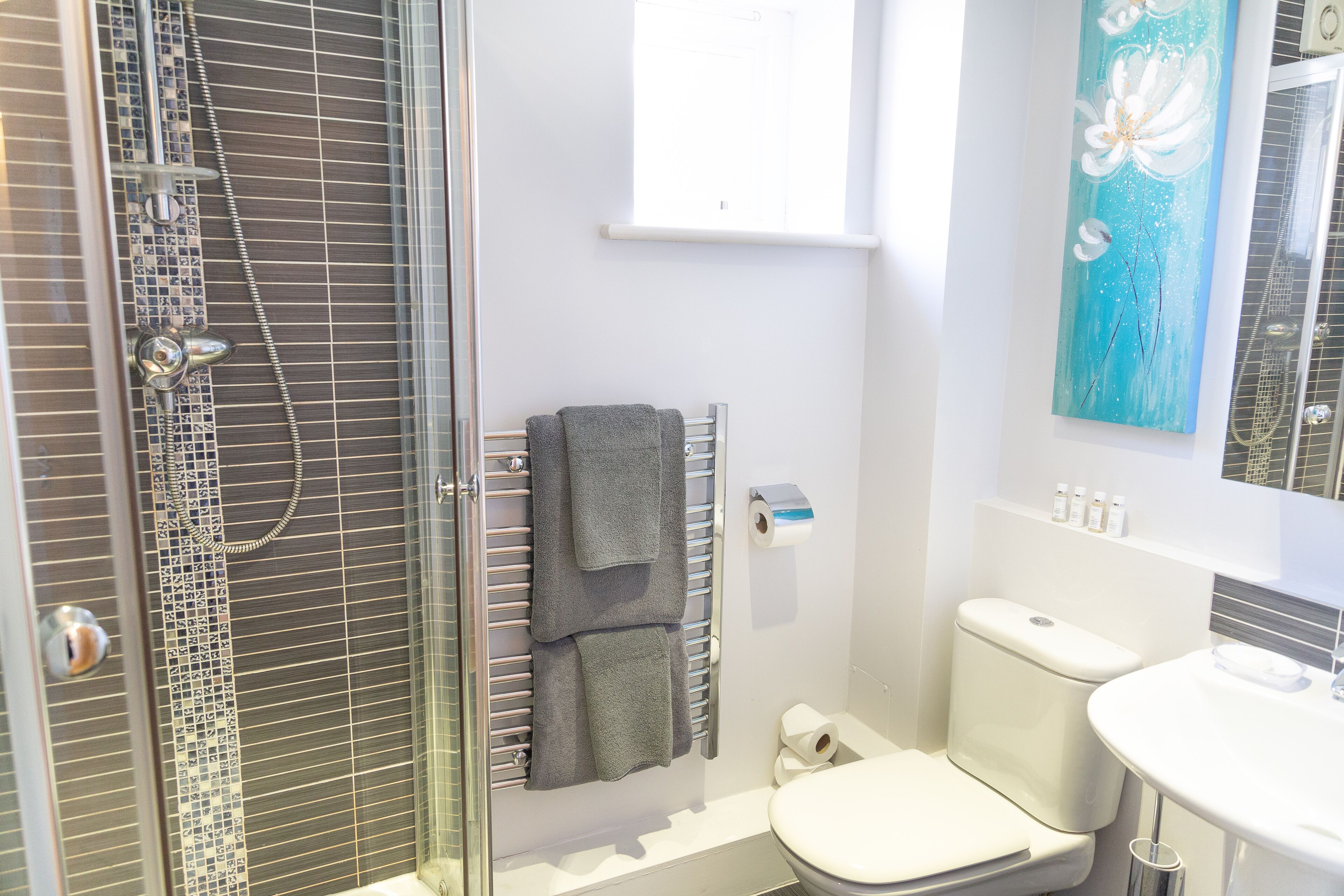 A bathroom with a glass-enclosed shower, a toilet, and a sink.