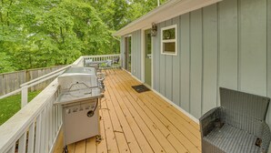 Eine Terrasse mit Grill, einem Korbstuhl und einem Holzaumschlag.