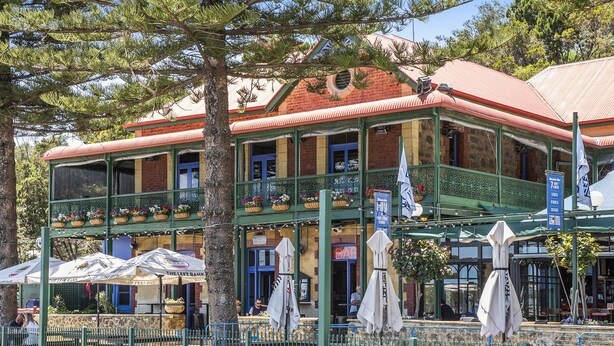 A two-story building with a balcony, outdoor seating, and a sign indicating a restaurant. - Beautifully renovated studio apartment in Fremantle (Fremantle)