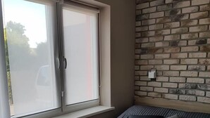 Une pièce avec un lit, une fenêtre et un mur en briques.