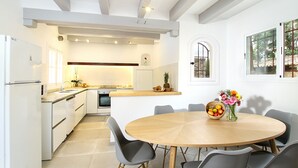 Una cucina moderna con mobili bianchi, un tavolo da pranzo in legno e una ciotola di frutta.