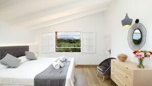 Una camera da letto con un letto, una finestra vista verde, una scrivania con un vaso di fiori e una sedia.