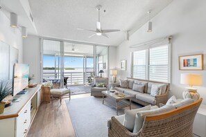 A spacious living area with a large window, a ceiling fan, and a dining area with a table and chairs.