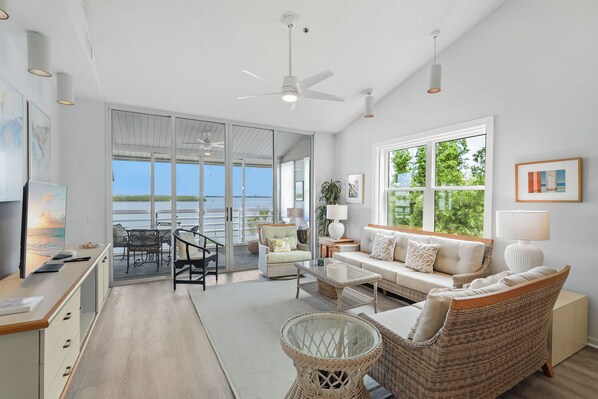 A spacious living area with a large window, a ceiling fan, and a view of the outdoors.