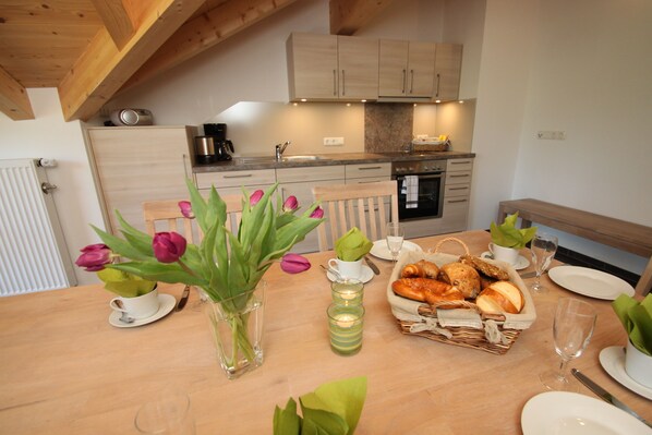 Una mesa de comedor con tulipanes, una vela y una cesta de pan.
