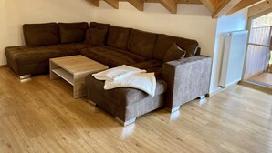 Un sofá seccional en forma de L con un reposapiés a juego, una mesa de centro de madera y un radiador.
