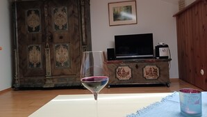 Une pièce avec un meuble en bois, un téléviseur posé sur un meuble, et un verre dont le bord est violet.