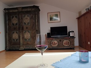 A room with a wooden cabinet, a television on a stand, and a glass with a purple rim.